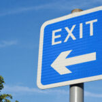 Exit sign in blue and white with a right arrow, indicating direction on a road in Aberdeen.